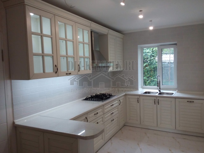 Light beige kitchen with a sink under the window and a bar