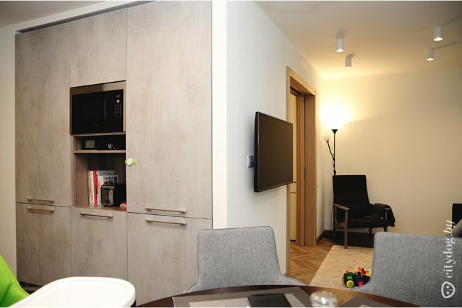 Virtuves-viesistabas dizains vienvietīgā istabā ar balkona durvīm