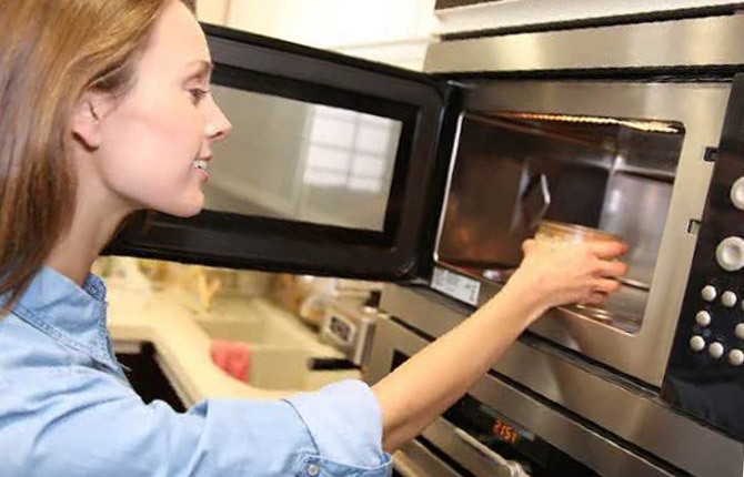Dziewczyna podgrzewania jedzenia w kuchence mikrofalowej