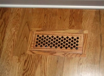 Grătar de ventilație în podeaua unei case din lemn