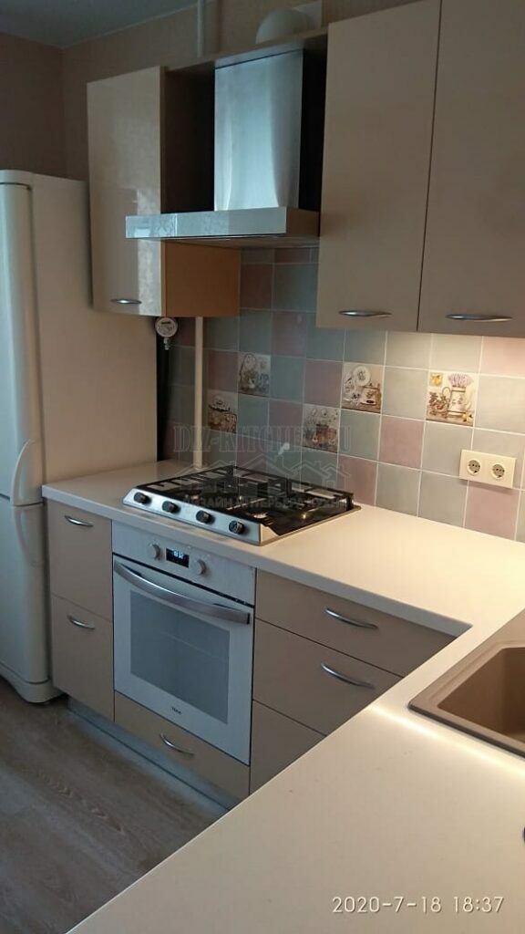 Modern beige corner kitchen with TV on the wall