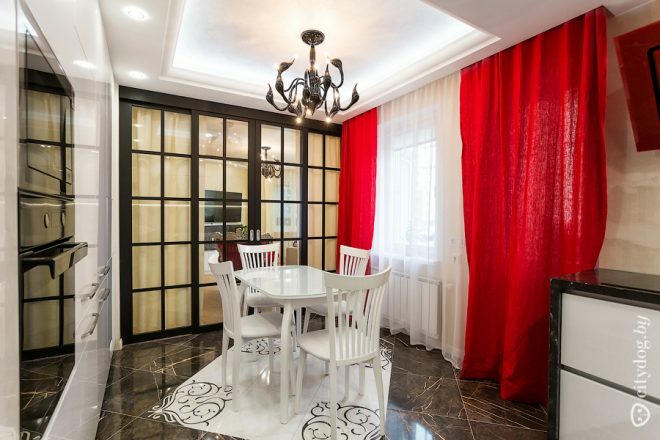 Rdeče zavese v beli kuhinji s površino 12 kvadratnih metrov.