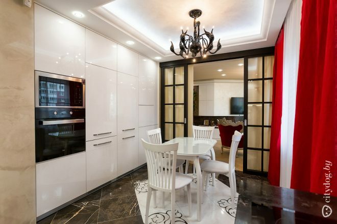 Rdeče zavese v beli kuhinji s površino 12 kvadratnih metrov.