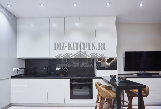 Bílá rohová kuchyně s barovým pultem spojená s obývacím pokojem