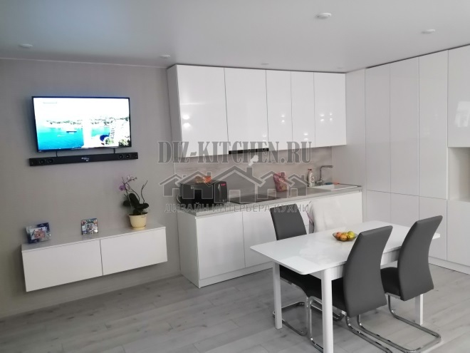 Cocina moderna blanca brillante combinada con sala de estar.