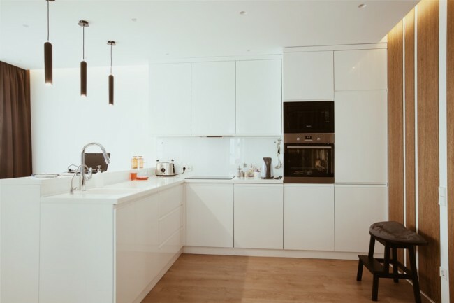 Moderná biela kuchyňa bez úchytiek. Barový pult s umývadlom